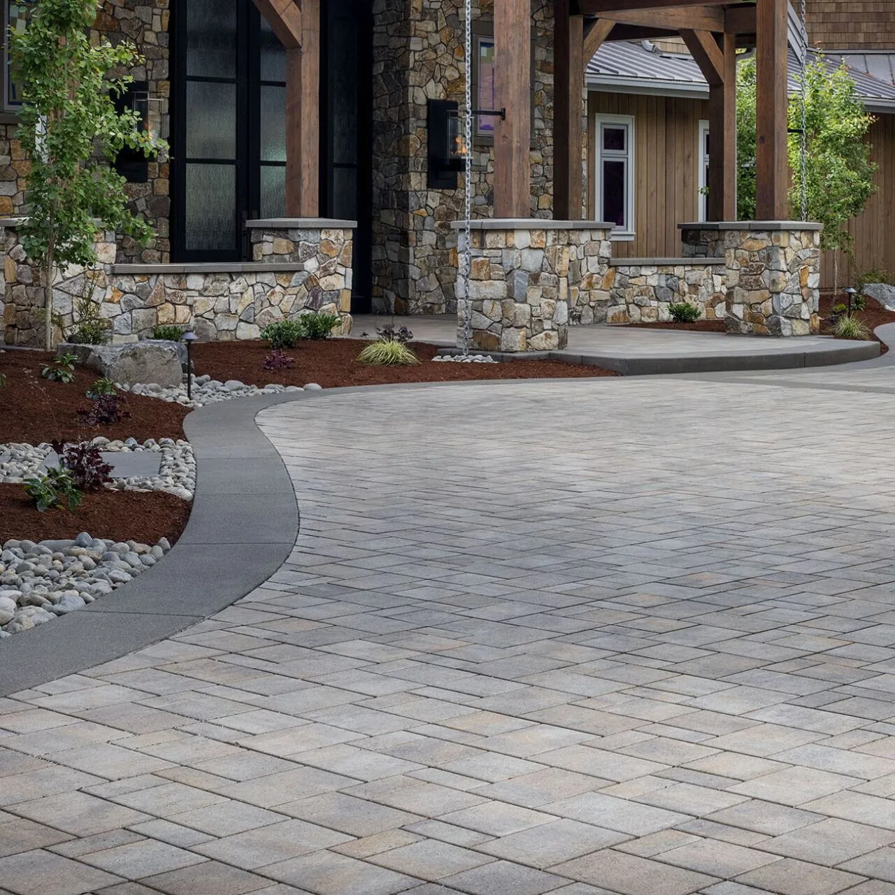 Estate paver driveway with stone pillars and landscaping