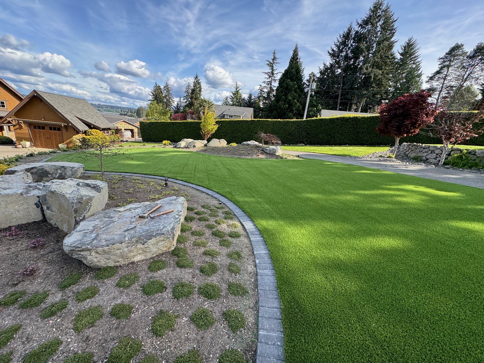 Backyard artificial turf and boulder landscape